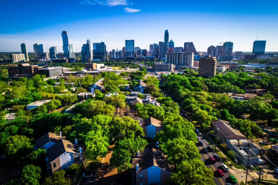 Aerial view of green trees over residential neighborhood with Austin, Texas skyline in the background